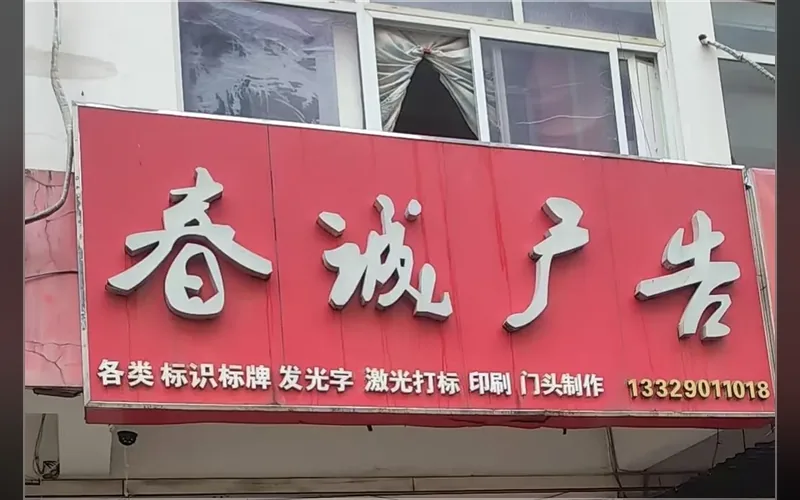 合肥春诚激光打标包河区实体门店门头实拍 · 红色招牌写明各类标识标牌、发光字、激光打标、印刷、门头制作，招牌下沿留电话 13329011018
