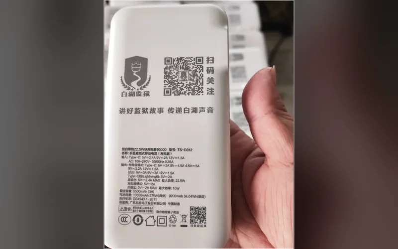 合肥激光打标代工实拍 · 白色移动电源充电宝表面激光打标单位徽标、二维码和「扫码关注」字样，背面参数同批打全，批量出货逐个一致、二维码可扫可识别